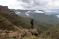 Wanderer auf einem Felsvorsprung mit Blick auf das bergige Gelände.