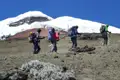 Wanderer besteigen einen Berghang mit Schneebedeckung im Hintergrund.