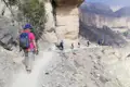 Wanderer mit Rucksäcken und Wanderstöcken auf einem Bergpfad.