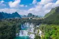 Mehrstufiger Wasserfall in einer grünen, hügeligen Landschaft.