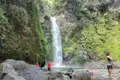 Wanderer pausieren am Fuße eines Wasserfalls.