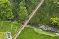 Hängebrücke über einen Fluss mit Reisfeldern im Vordergrund.