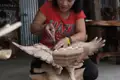 Kunsthandwerkerin beim Schnitzen einer Adler-Skulptur aus Holz.