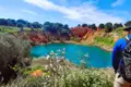 Türkisfarbener See umgeben von roter, felsiger Landschaft.