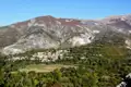 Panoramablick auf ein Bergdorf, umgeben von herbstlicher Vegetation und felsigen Berghängen.