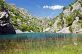 Blauer See inmitten einer felsigen Hügellandschaft.