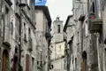 Enge Straße in einem italienischen Dorf mit Blick auf einen Kirchturm.