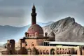 Historische Gebäude und ein Minarett vor einem Berg.