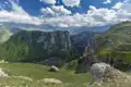 Panoramablick auf eine tiefe Schlucht mit bewachsenen Hängen und Felsformationen.