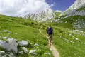 Wanderer auf einem Bergpfad mit felsigen Gipfeln im Hintergrund.