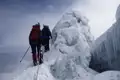 Zwei Bergsteiger besteigen einen verschneiten Berggrat mit Eisformationen.