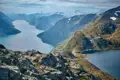 Panoramablick auf einen Fjord und schneebedeckte Berge von einem felsigen Aussichtspunkt.