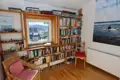 Blick in die Leseecke der Unterkunft. Bücherregale und ein Sessel laden zum Verweilen ein. Das Fenster bietet einen Blick auf die umliegende Landschaft.