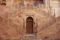 Sandsteintreppe mit kunstvollen Details und einer geschnitzten Holztür.