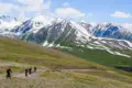 Mountainbiker auf einem Bergpfad mit schneebedeckten Bergen im Hintergrund.