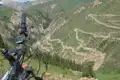 Blick vom Mountainbike-Lenker auf eine kurvenreiche Bergstraße.