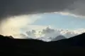 Schneebedeckte Berglandschaft mit dramatischen Wolken und Regenschauer.