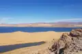 Panoramablick auf einen See, umgeben von Sanddünen und Bergen.