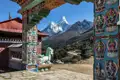Blick durch ein kunstvoll verziertes Tor eines buddhistischen Tempels auf die schneebedeckten Himalaya-Gipfel.