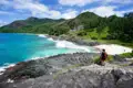 Wanderer mit Blick auf eine abgelegene Bucht mit weißem Sandstrand und türkisfarbenem Wasser.