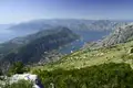 Aussicht auf die Bucht von Kotor von einem erhöhten Standpunkt aus.  Die Landschaft zeigt die Berge, das Wasser und die Küstenstädte.