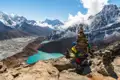 Türkisfarbene Gletscherseen im Himalaya mit Blick auf die schneebedeckten Gipfel und Gebetsfahnen an einem Steinhaufen.