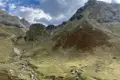Gebirgstal mit Hütten und Bachlauf.
