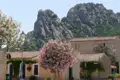 Szene eines Dorfplatzes mit traditionellen Häusern und einem großen Felsen im Hintergrund.