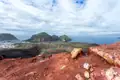 Panoramablick auf eine grüne Insel vom roten, felsigen Aussichtspunkt aus.