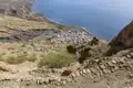 Blick von einem steilen Pfad auf eine Küstensiedlung und das Meer.