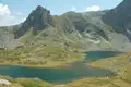 Zwei Bergseen in einer hochalpinen Landschaft mit felsigen Gipfeln und grünen Hängen.