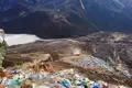Gebetsfahnen markieren einen Aussichtspunkt mit Blick auf ein Hochtal, einen Fluss und eine Siedlung.