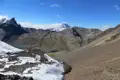 Hochgebirgspanorama mit Schnee, Seen und Bergpfad.