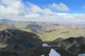 Aussicht von einem Berggipfel auf eine Hochgebirgslandschaft mit Seen und Tälern.