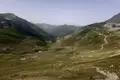 Blick auf ein Bergtal mit grünen Hängen und einem gewundenen Pfad.