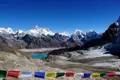 Gebetsfahnen im Vordergrund einer Himalaya-Berglandschaft mit Gletscher und See.