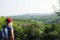 Wanderer betrachtet die Weinberge und ein Dorf in der Hügellandschaft.
