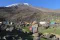 Basislager mit Zelten und Bergsteigern, bereit für die Besteigung des schneebedeckten Berges.