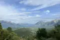 Aussicht auf ein Gebirgstal mit bewaldeten Hängen und Bergen im Hintergrund.