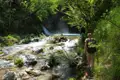 Wanderer auf einem Flussweg in der Nähe eines Wasserfalls.