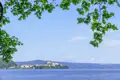 Blick auf den See und die Stadt am Ufer, umgeben von einer hügeligen Landschaft.