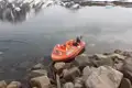 Orangefarbenes Boot am Ufer eines Bergsees, bereit für eine Erkundungstour.