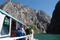 Ausflugsboot mit Passagieren fährt durch eine Schlucht mit hohen, steilen Felswänden und türkisgrünem Wasser.