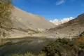 Panoramablick auf einen Bergsee mit schneebedeckten Gipfeln im Hintergrund.
