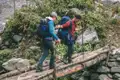 Wanderer überqueren eine Holzbrücke im Gebirge.