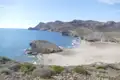 Abgelegene Bucht mit Sandstrand und Felsformationen im Hintergrund.