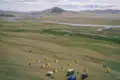 Blick auf das Reisecamp mit Zelten in der Nähe eines Flusses und Hügellandschaft.