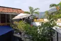 Terrasse mit Sonnenschirm, Pflanzen und Blick auf die Berge.