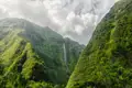 Spektakulärer Wasserfall, der zwischen zwei üppig bewachsenen Bergen inmitten einer dramatischen Landschaft hinabstürzt.
