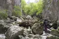Wanderer in einer engen, felsigen Schlucht mit großen moosbewachsenen Felsen.
